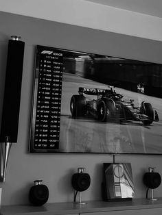 a black and white photo of a racing car on the wall above a shelf with speakers