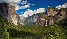 the mountains are covered with trees and waterfalls