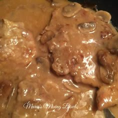 meat and mushrooms covered in gravy on top of a pan with sauce over it