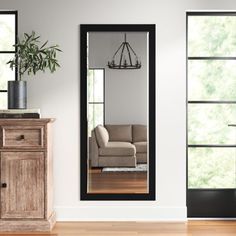 a mirror sitting on top of a wooden dresser next to a couch in a living room