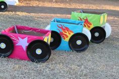 three small toy cars sitting on top of a grass covered field next to each other