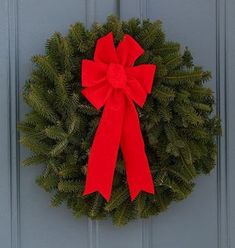 a wreath with a red bow hanging on a door