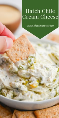 a hand dipping a cracker into a bowl of cream cheese