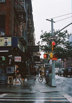 people crossing the street at an intersection on a rainy day