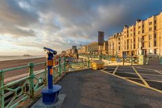 an empty parking lot next to the ocean with buildings in the background and cloudy skies