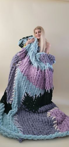 a woman sitting on top of a blanket covered in crochet