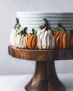 a cake decorated with pumpkins on a wooden stand