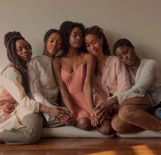 four women sitting on the floor with their arms around each other