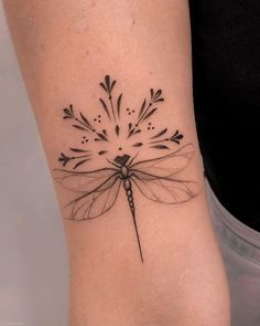 a black and white photo of a dragonfly tattoo on the right arm, with arrows coming out of it