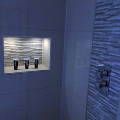 a bathroom with three black vases on the wall and two lights in the window