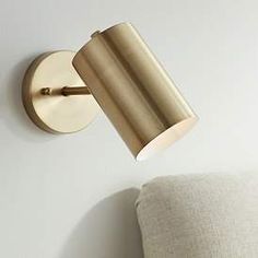 a light that is on the side of a wall next to a chair and pillow