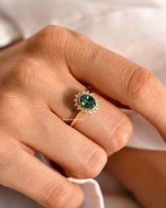 a woman's hand with a green ring on it