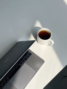 an open laptop computer sitting on top of a table next to a cup of coffee