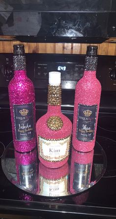 three pink bottles with gold glitter on them