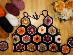 a crocheted purse and several balls of yarn on a wooden table with flowers