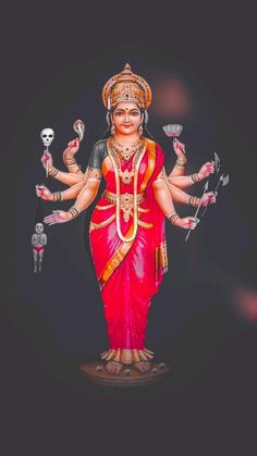 a statue of the hindu god in red and gold with skulls on his hands,