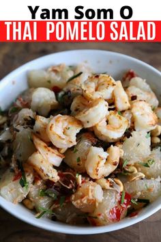 a bowl filled with shrimp and vegetables on top of a wooden table next to the words, yam som o thai pomelo salad