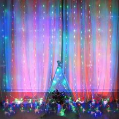 a teepee tent with lights on it in front of a curtain