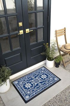 a blue door mat sitting on the side of a building next to a chair and potted plant