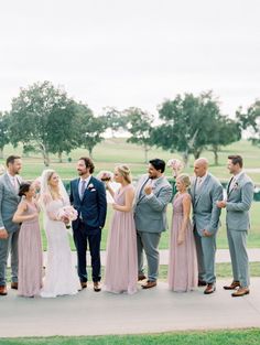 a group of people standing next to each other on top of a cement slab in front of a lush green field