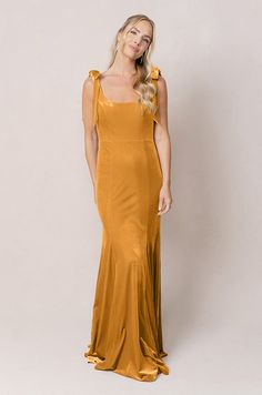 Model: Britt; Size: 4; Color: Mustard Formal Maxi Dress With Square Neck In Solid Color, Formal Maxi Dress With Square Neck, Formal Solid Maxi Dress With Square Neck, Formal Solid Color Maxi Dress With Square Neck, Elegant Square Neck Maxi Dress With Tie Back, Square Neck Dress With Ruched Back And Fitted Bodice, Formal Square Neck Dress With Bias Cut, Elegant Midi Dress With Ruched Back And Square Neck, Elegant Midi Dress With Square Neck And Ruched Back