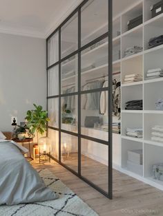 a bedroom with white walls and shelves filled with clothes, plants and candles on the floor