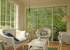 a living room with wicker furniture and large windows