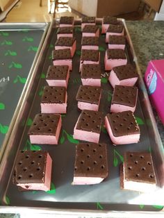 some pink and brown ice cream sandwiches on a tray