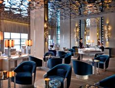 the interior of a fancy hotel with blue chairs and chandeliers on the ceiling