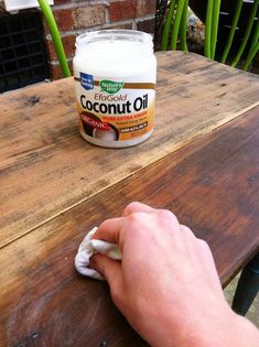 a person wiping off the top of a table with a cloth on it and a jar of coconut oil