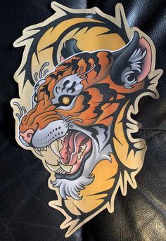 an image of a tiger head on the back of a black leather jacket with gold accents