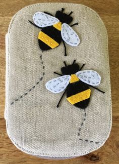 two bees sitting on top of a piece of cloth with yellow and black patches in the middle