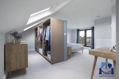 an attic bedroom with white carpeting and skylights above the bed, closet doors open to let in plenty of light