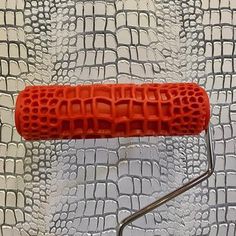 a red object sitting on top of a white table next to a metal wallpaper