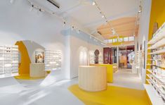 the interior of a store with shelves and eyeglasses on display in yellow and white colors