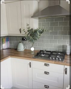 a kitchen with white cabinets and a stove top oven next to a vase filled with flowers