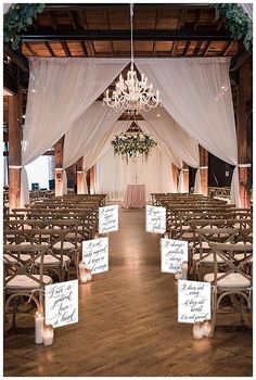 an indoor wedding venue with white drapes and chandelier hanging from the ceiling