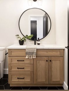 a bathroom with a round mirror above the sink and wooden cabinetry on the counter