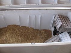 an open freezer filled with lots of brown food next to plastic containers on the floor