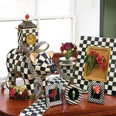 a table topped with black and white checkered paper animals next to framed pictures, flowers and vases