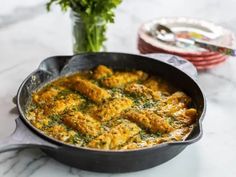 a pan filled with food sitting on top of a table next to a vase of flowers