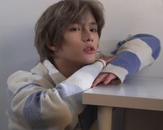 a young boy sitting at a table with his arms folded