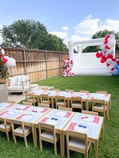 an outdoor party setup with balloons and decorations on the lawn, including tables and chairs