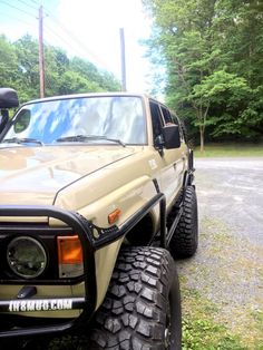 an off - road vehicle is parked on the side of the road in front of some trees