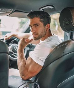 a man sitting in the driver's seat of a car with his hand on his chin