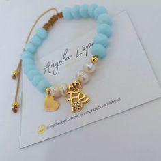 a bracelet with two charms on it and a tag attached to the beaded bracelet