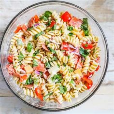 a bowl filled with pasta salad on top of a wooden table