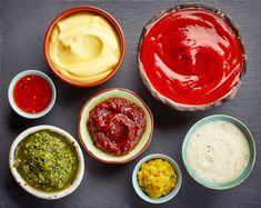 various sauces and condiments are arranged in small bowls on a black surface