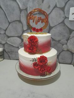 a three tiered cake with red flowers on top