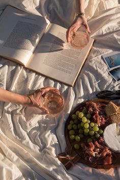 a person laying in bed with an open book and glass of wine